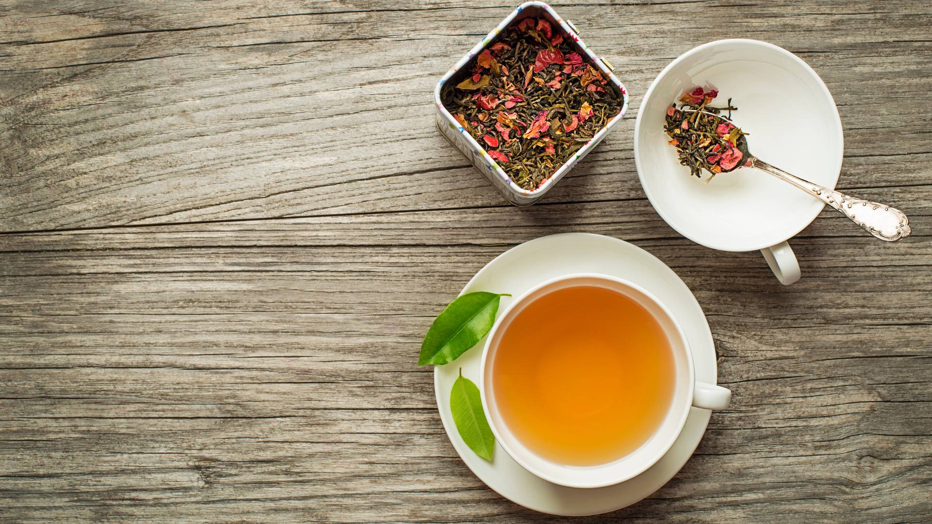 Cup of dark herbal tea with dried root herbs on wooden surface, soothing herbal tea for gut inflammation support