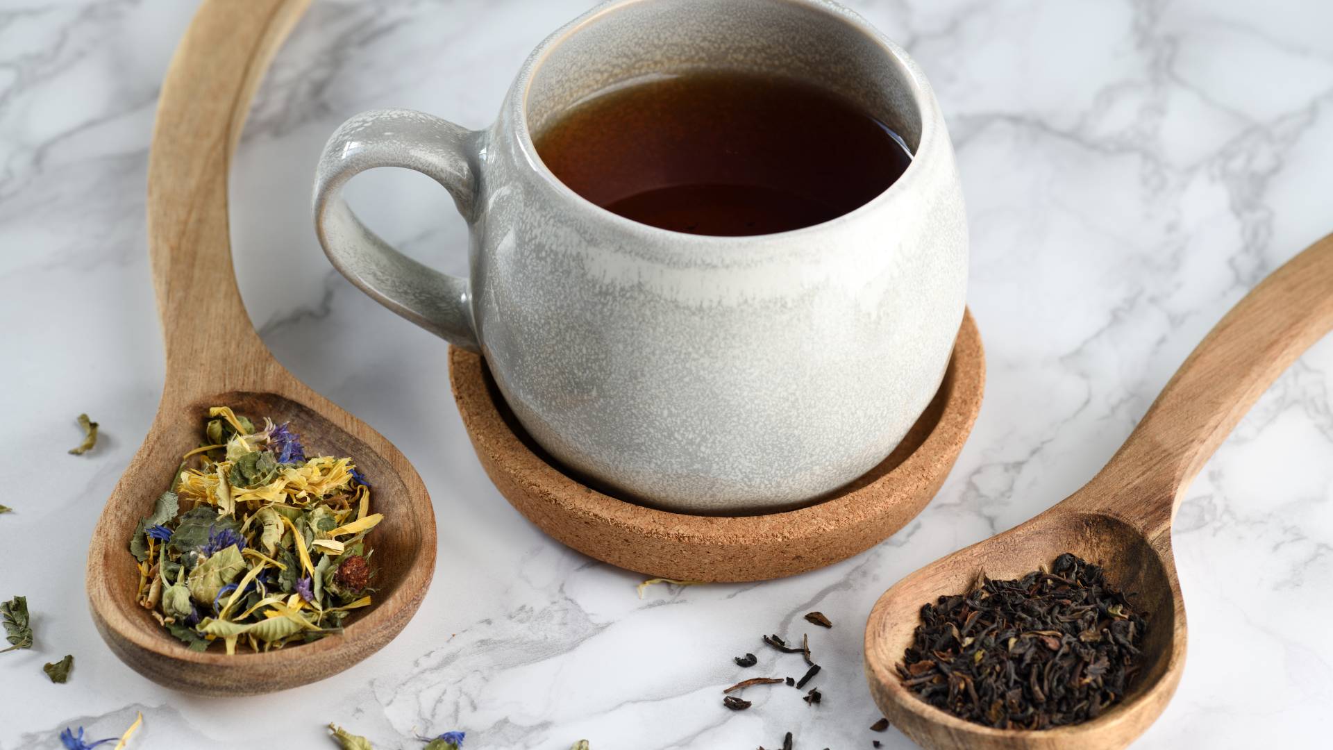 Cup of herbal tea with dried herbs on wooden spoons, refreshing herbal tea for clarity support