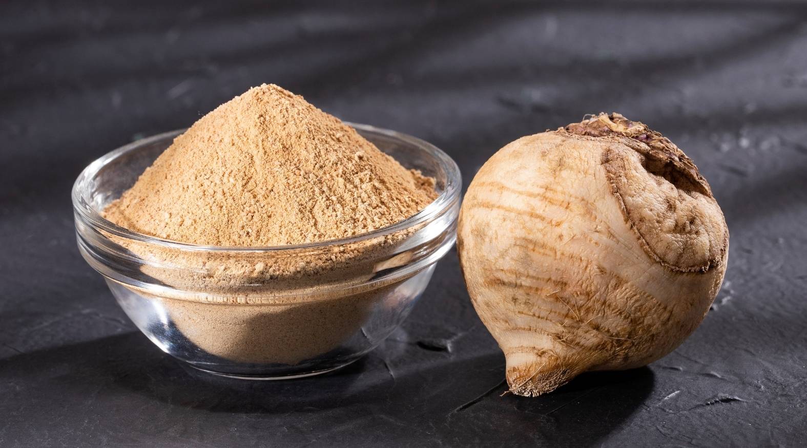 Maca root (Lepidium meyenii) showing a whole dried root alongside a bowl of finely ground maca powder, highlighting its earthy tones and natural texture.