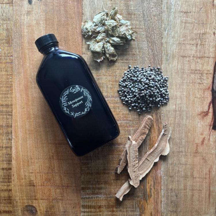Herbal tincture bottle with dried herbs on wooden surface, natural herbal tea for menopause support