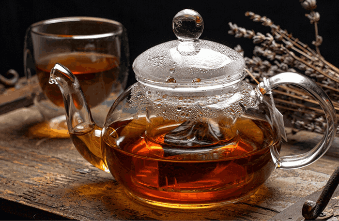 A warm cup of herbal tea after overeating, served in a glass teapot for a comforting post-meal ritual.