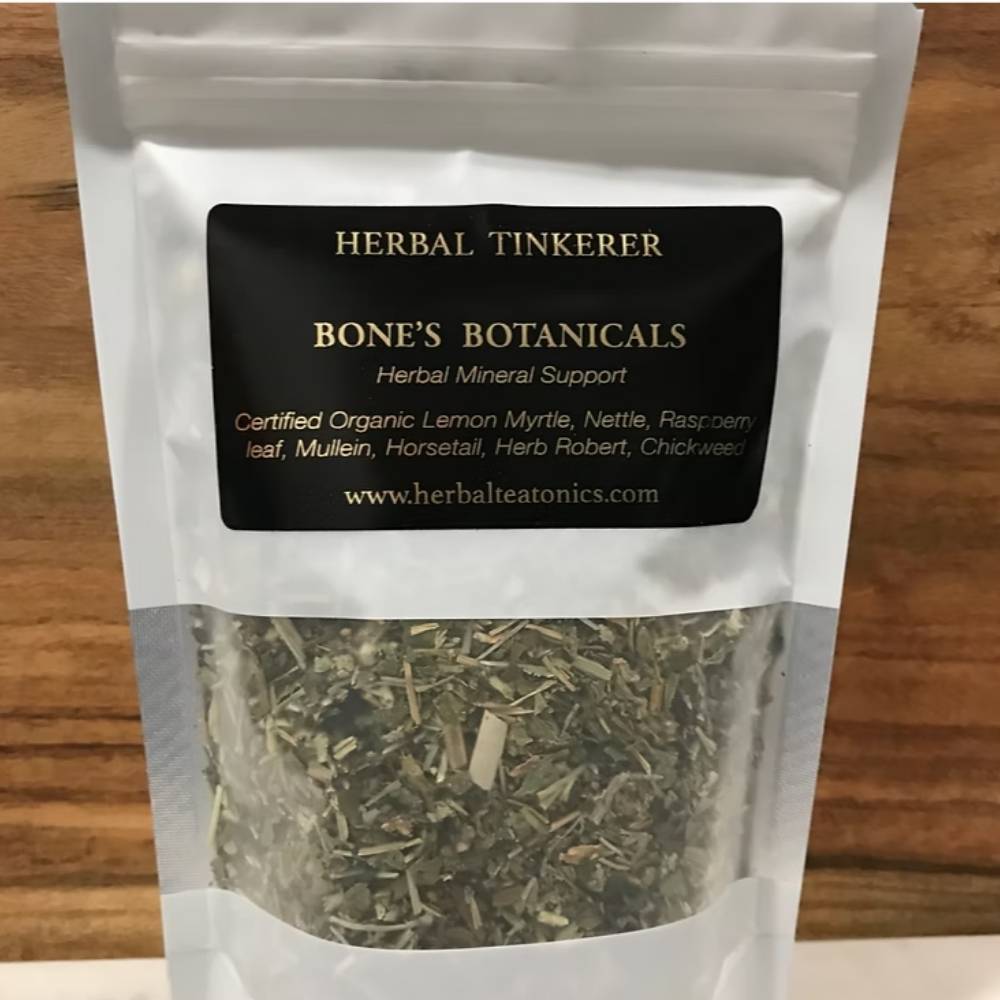 Packaged herbs labeled 'Herbal Tinkerer Bone's Botanicals' on a wooden surface