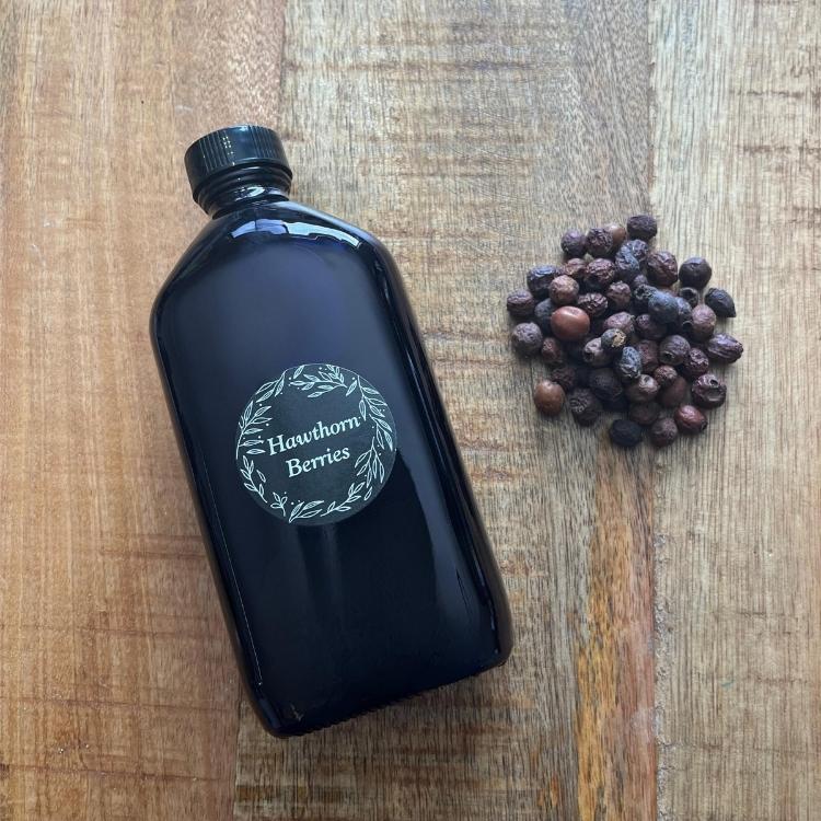 Black bottle labeled 'Hawthorn Berries' on a wooden surface with dried berries.