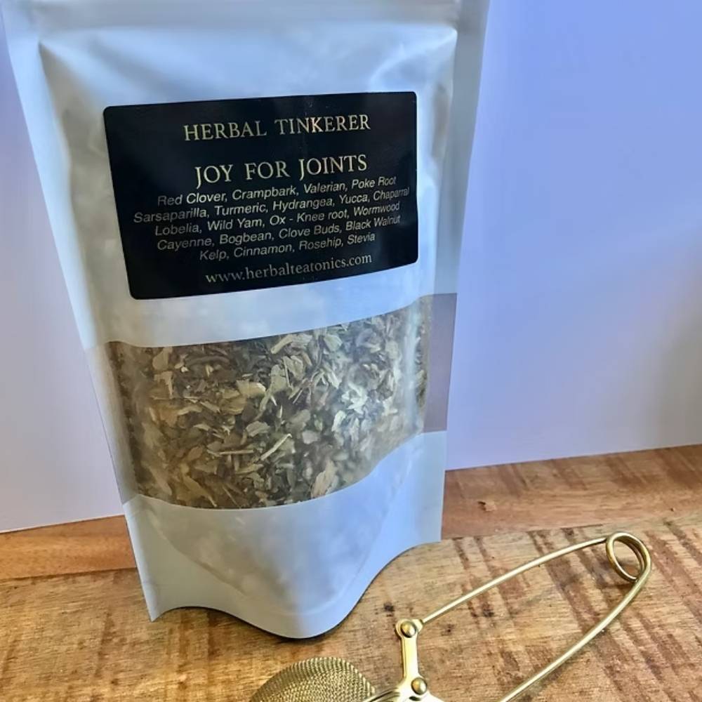 Herbal tisane package labeled 'Joy for Joints' by Herbal Tinkerer on a wooden surface.